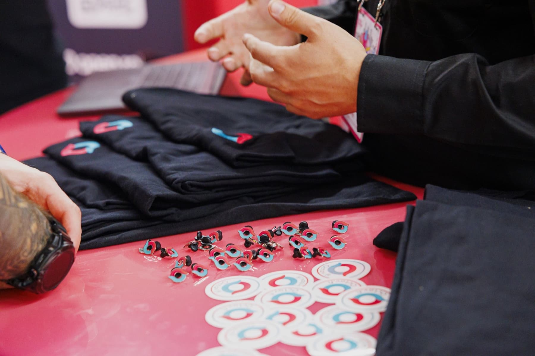 Octav tees, enamel pins and stickers on the booth counter